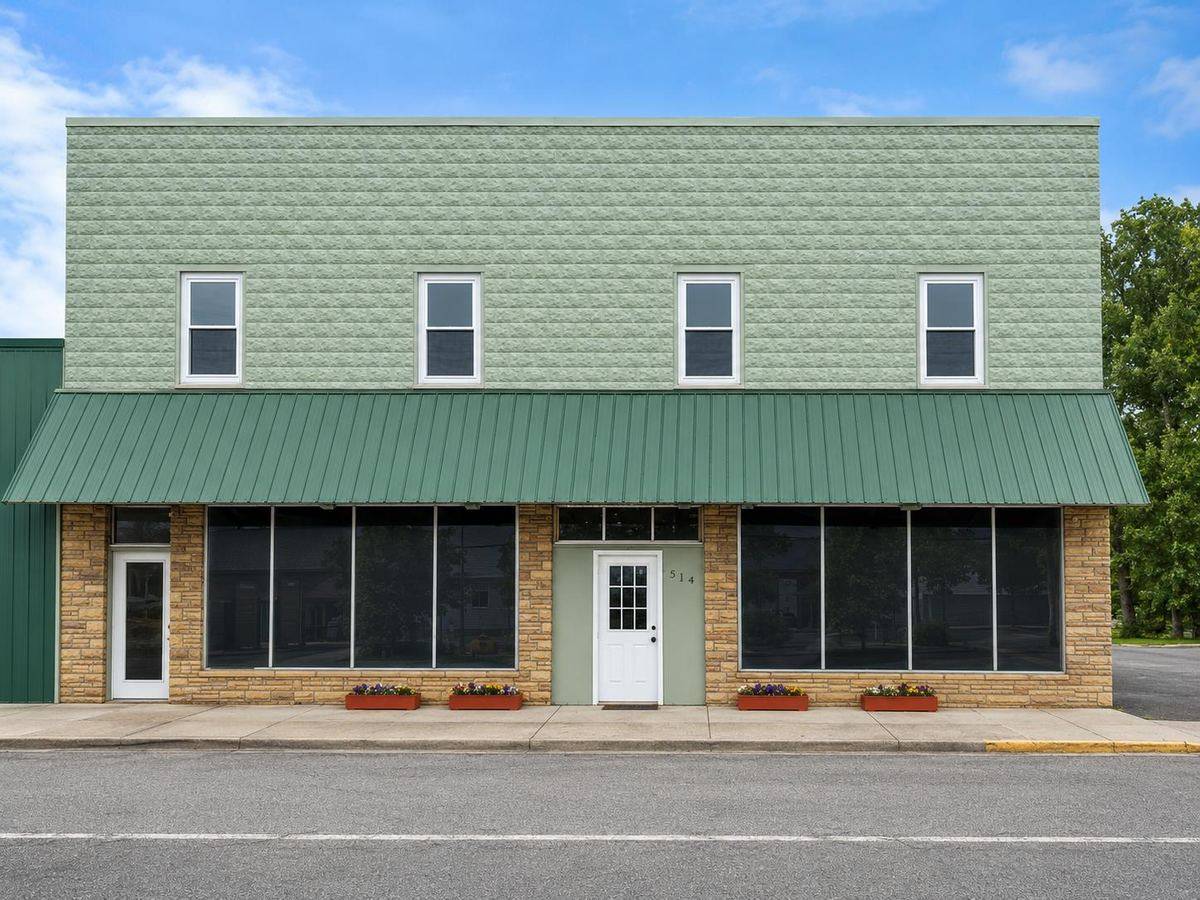 Front exterior of Meadow River Lofts, a two-story green building with a metal awning and street-level storefronts